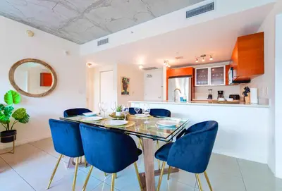 a dining room with a glass table and blue chairs at Stylish Midtown Miami Condo - Pool & Prime Location in Miami
