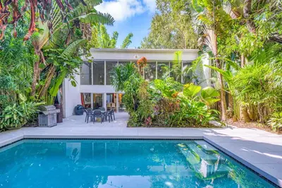 a home with a swimming pool in front of a house at Wonderful Tropical Pool House Miami Coconut Grove in Miami