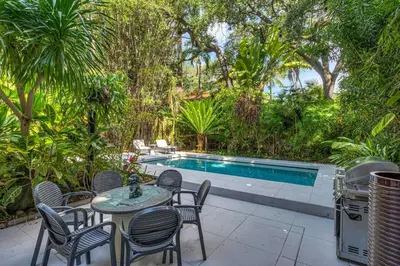 a patio with chairs and a table and a swimming pool at Wonderful Tropical Pool House Miami Coconut Grove in Miami