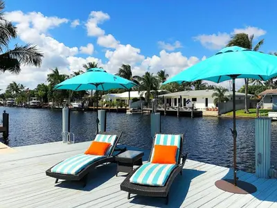 two chairs and umbrellas on a dock with a body of water at Waterfront Oasis with Pool, Sunset Views and Dock in Fort Lauderdale