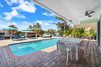 a patio with a table and chairs next to a swimming pool at Waterfront Oasis with Pool, Sunset Views and Dock in Fort Lauderdale