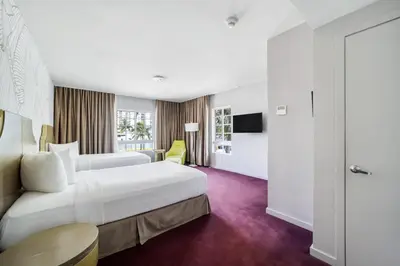 a hotel room with a large white bed and a window at Alamo Hotel in Miami Beach