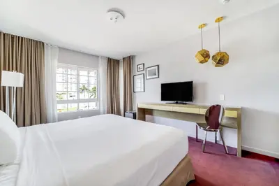 a hotel room with a bed and a desk and a television at Alamo Hotel in Miami Beach