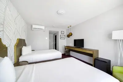 a hotel room with two beds and a desk at Alamo Hotel in Miami Beach