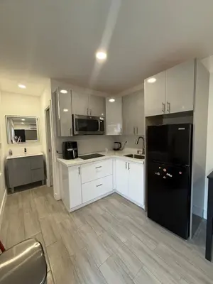 a kitchen with white cabinets and a black refrigerator at Modern and private studio in Miami