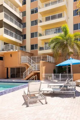 two lounge chairs and an umbrella next to a building at Tiny Tower Treasure - Sleeps 5 & Soaks Sun in Sunny Isles Beach