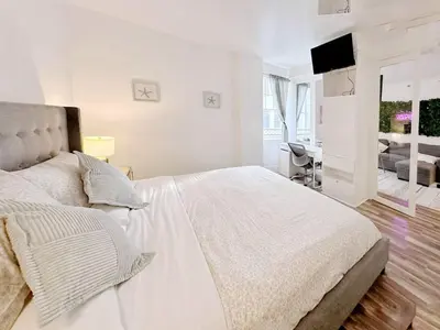 a white bedroom with a bed and a television at Pool and Jacuzzi. Walk to beach, South Point Pier in Miami Beach