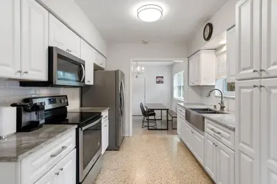 a kitchen with white cabinets and a sink and a refrigerator at 2 Bedroom Cozy House Near Barry University in Miami