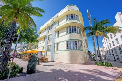 a yellow and white building with palm trees in front of it at Right on the beach, Ocean Drive Secured Condo in Miami Beach