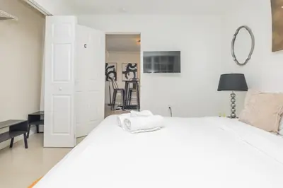 a white bedroom with a white bed and a table at Charming 3BR Getaway - Central Miami Location in Miami