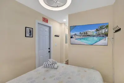 a bedroom with a bed and a tv on the wall at Charming Beachside Studio - Steps to the Beach in Hollywood