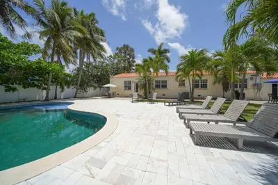 a swimming pool with lounge chairs and palm trees at Hollywood Beach Bliss Villa Sleeps 10 in Hollywood