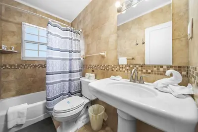 a bathroom with a sink and a toilet and a mirror at Hollywood Beach Bliss Villa Sleeps 10 in Hollywood
