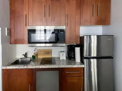 a kitchen with wooden cabinets and a stainless steel refrigerator at Right on the Beach Ocean Dr Secured Condo 206 in Miami Beach