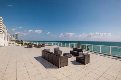 a row of benches sitting on a patio overlooking the ocean at Shine Suites Balcony Duplex 11 in Miami Beach