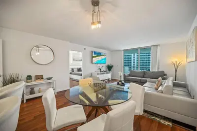 a living room with a glass table and white chairs at Skyline and Bay Glimpse 1BR Brickell Retreat in Miami