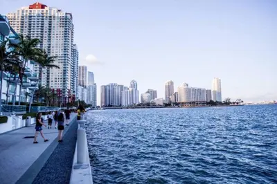 people walking on a sidewalk next to a body of water at Exclusive 2BR APT Brickell Free Parking in Miami