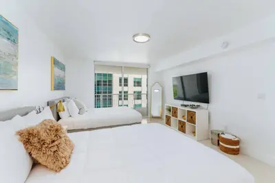 a white bedroom with two beds and a flat screen tv at Amazing 2BR at Brickell Free Parking in Miami