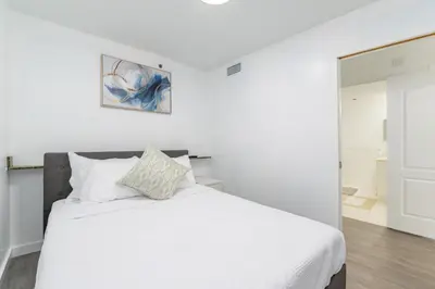 a white bedroom with a white bed and a mirror at 2bedroom ocean views brickell free parking in Miami