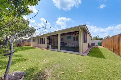 a house with sliding glass doors in a yard at 4 Mi to Hard Rock Stadium Miramar Home with BBQ! in Miramar
