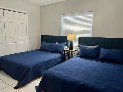 a bedroom with two beds with blue sheets and a window at Coral Gable 3BR House in Miami