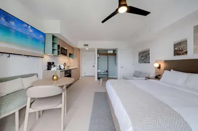 a bedroom with a large white bed and a kitchen at Bellini Breeze - Cozy Central Miami Pool and Gym in Miami
