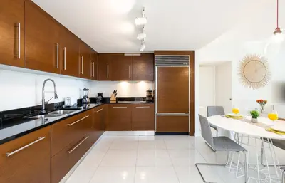 a kitchen with wooden cabinets and a white table at MVR - Where Views Meet Vibes in Miami in Miami
