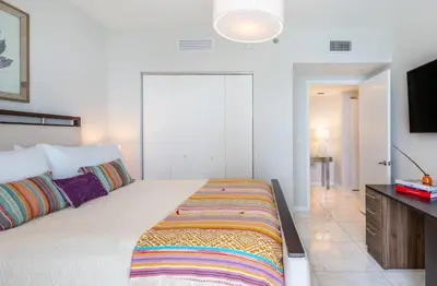 a white bedroom with a large bed and a tv at MVR - The Ultimate Brickell Balcony in Miami