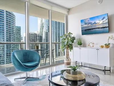 a living room with a blue chair and large windows at MVR - High-Rise Escape with Spa Access in Miami