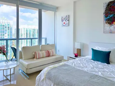a bedroom with a bed and a couch and a window at MVR Brickell Gem w Designer Touches in Miami