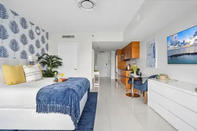 a white bedroom with a large bed and a kitchen at MVR Sleek Condo with Iconic Views in Miami