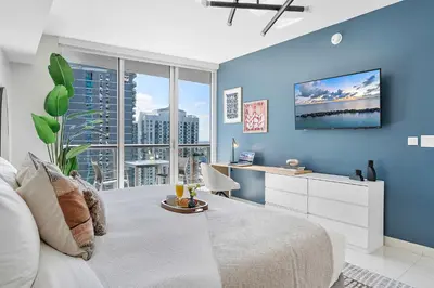 a bedroom with blue walls and a large window at MVR - Wake Up to Brickell-s Best Views in Miami
