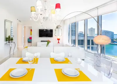 a dining room with a white table and yellow accents at MVR - High-Floor Luxury with Iconic Views in Miami
