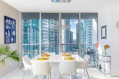 a white dining room with a white table and white chairs at MVR - Sky-High Style in Brickell in Miami