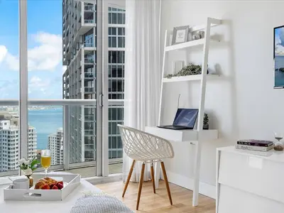 a white kitchen with a desk with a laptop and a window at MVR - Bay & City Views from the 45th in Miami