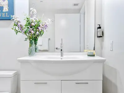 a bathroom with a white sink with a vase of flowers at MVR - Bay & City Views from the 45th in Miami