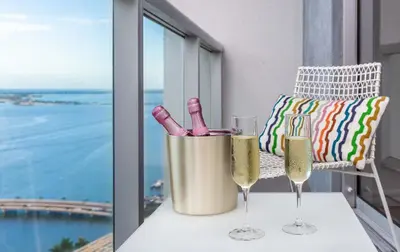 two wine glasses and wine bottles on a balcony at MVR - Soaring Views & Spa Access in Miami