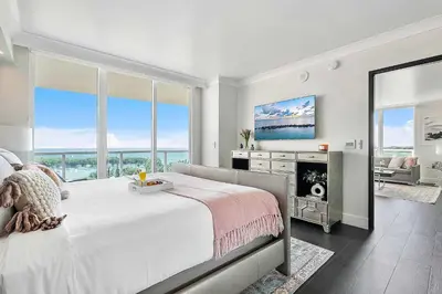 a white bedroom with a large bed and a tv at MVR - Elevate Your Stay with Panoramic Bay Views in Miami