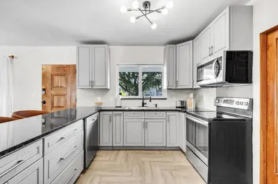 a kitchen with white cabinets and black appliances at 4BR Biscayne River Home with Pool & Pickleball Fun in Biscayne Gardens