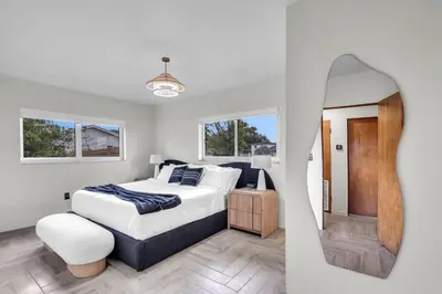 a white bedroom with a large bed and a mirror at 4BR Biscayne River Home with Pool & Pickleball Fun in Biscayne Gardens