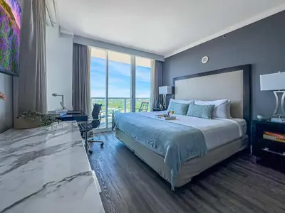 a hotel room with a large bed and a desk at MVR - Miami Vibes from Your Balcony Retreat in Miami