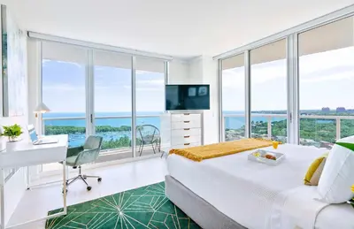 a hotel room with a bed and a desk and windows at MVR - Skyline Dreams from Your Private Balcony in Miami