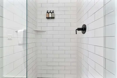 a white tiled shower with three bottles on a shelf at MVR - SupErhost Stay 10 Yrs of 5-Star Service in Miami