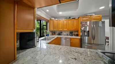 a kitchen with wooden cabinets and a stainless steel refrigerator at Luxury Queen Room, Walk to UM, Free Car Service! in Miami