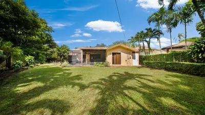 a house with a green yard with a palm tree at Luxury Queen Room, Free Car Service, Walk to UM! in Miami