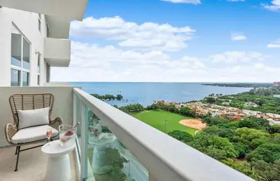 a balcony with a chair and a view of the ocean at MVR Suite with Poolside Sips and Biscayne Backdrop in Miami
