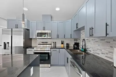 a kitchen with white cabinets and stainless steel appliances at Spacious 4-BR House W Free Parking in Miami