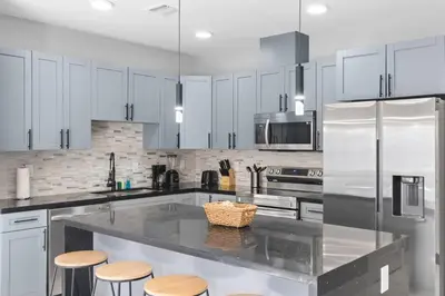 a kitchen with white cabinets and a kitchen island with stools at Amazing Townhouse w Free Parking in Miami