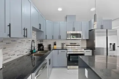 a kitchen with white cabinets and stainless steel appliances at Amazing Townhouse w Free Parking in Miami