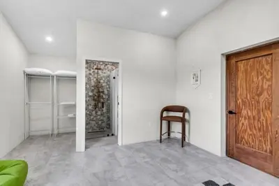 a white room with a wooden door and a chair at 4BR Biscayne River Home- Pool & Pickleball Fun home in Miami